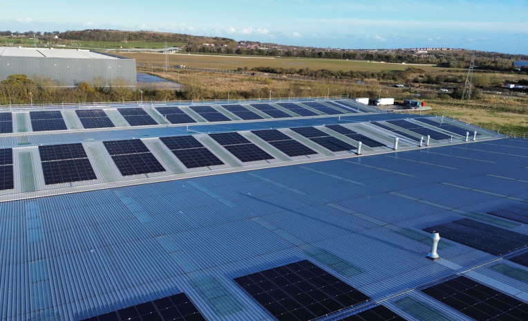 Industrial roof with photovoltaic panels and integrated skylight fall protection system for safe maintenance activities