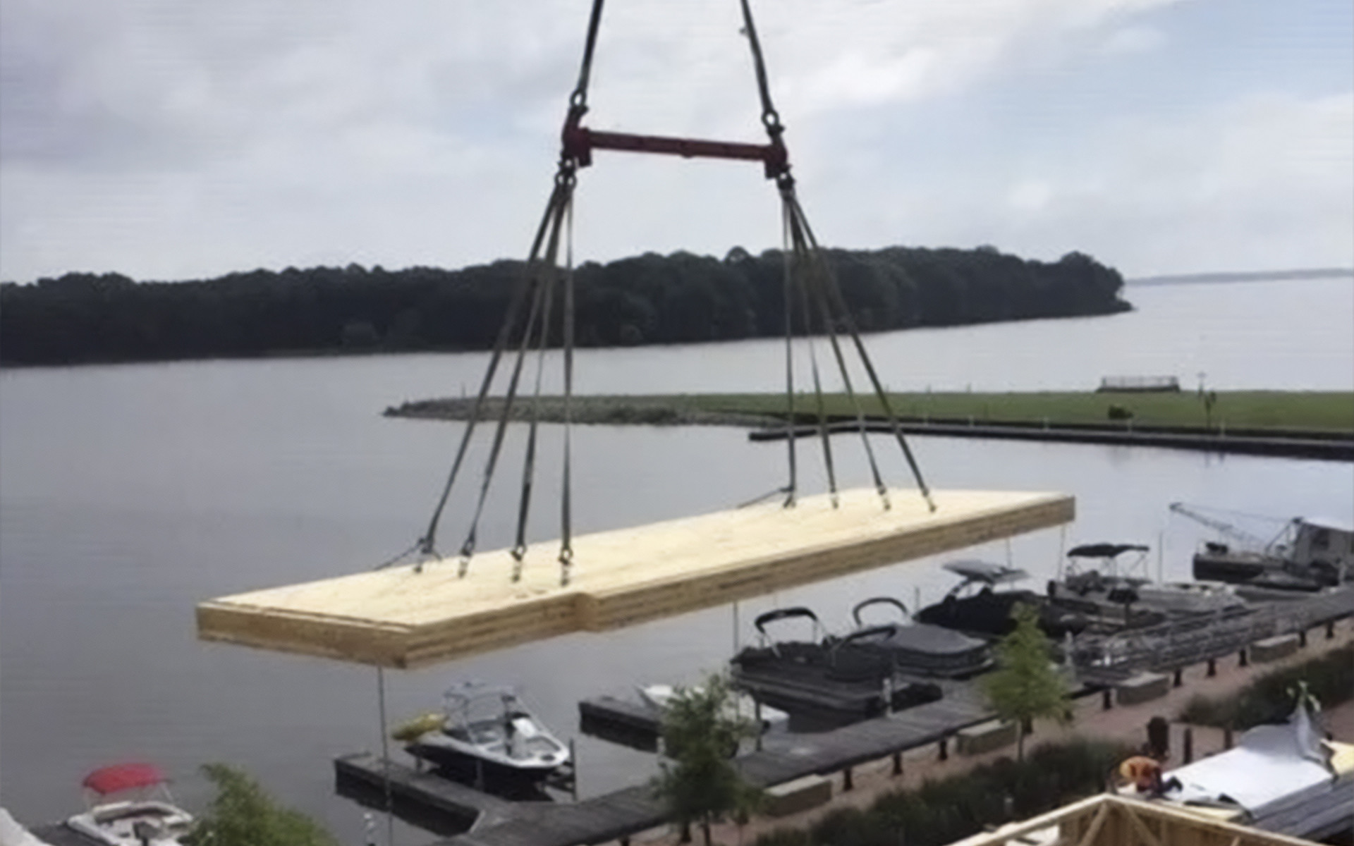 Crane lifting large prefabricated timber panel using multi-point lifting system on construction site for wooden prefabricated buildings
