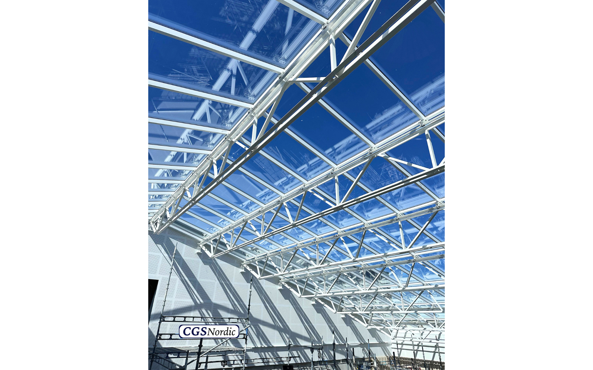 CGS Nordic technician wearing a white safety helmet and gloves, preparing H-RAIL rail components before installation in a glazed building atrium